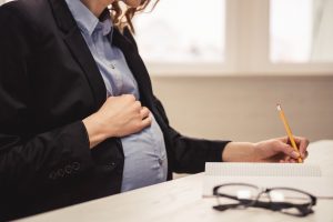 pregnant woman in business suit on computer at work looking for a discrimination lawyer columbus