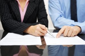 Two people checking paperwork at table, for professional contract negotiations meet with Chillicothe Contract Review Lawyers.