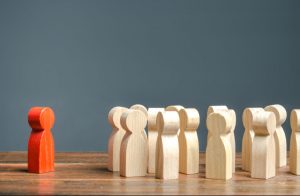 A group of wooden figures and one red figurine representing how a Columbus discrimination attorney can help you fight for your rights.